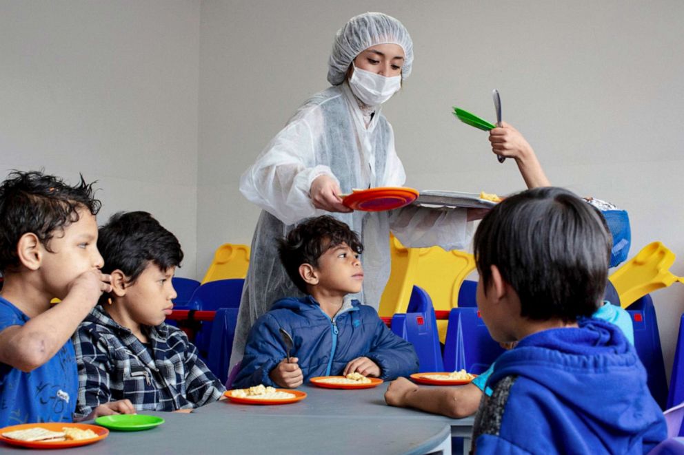 PHOTO: A staff member serves children their food during mealtime at El Centro Abrazar in Bogota, Jan. 20, 2020.