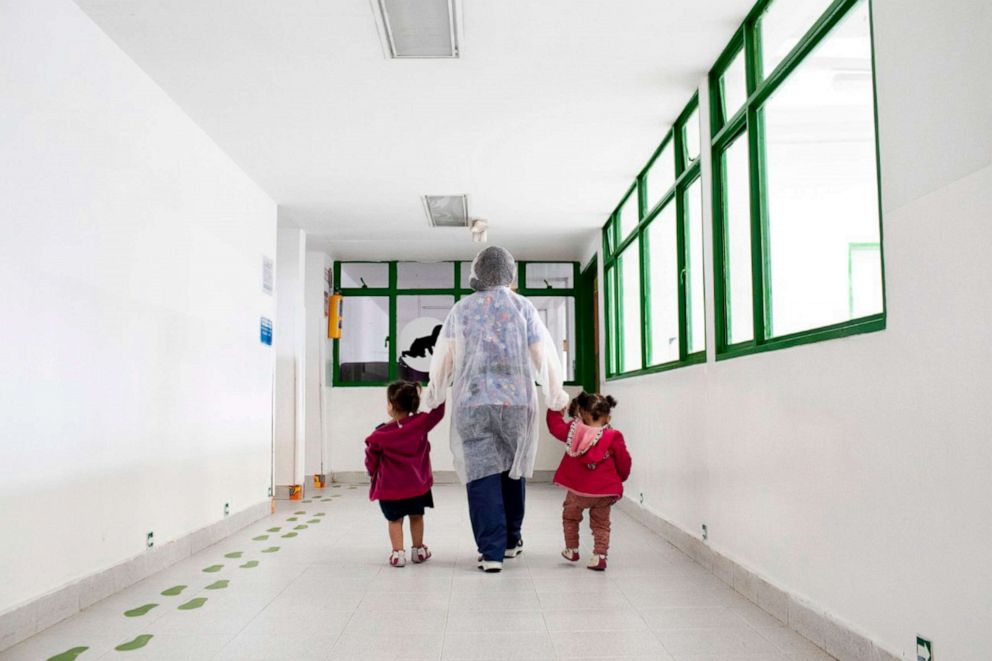 PHOTO: One of the center's caregivers walks with two children, leading them to a playroom at El Centro Abrazar in Bogota, Jan. 20, 2020.