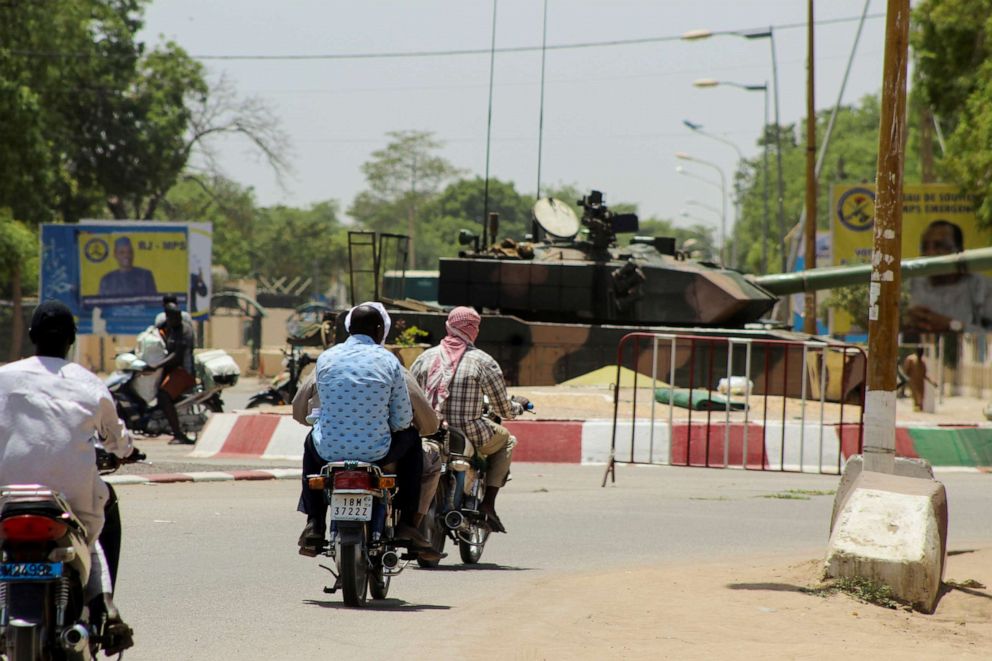 PHOTO: People drive past a Chadian army tank near the presidential palace in N'Djamena, Chad, on April 20, 2021, after Chadian President Idriss Deby Itno was killed on the front line in a battle against rebels in the north of the country.