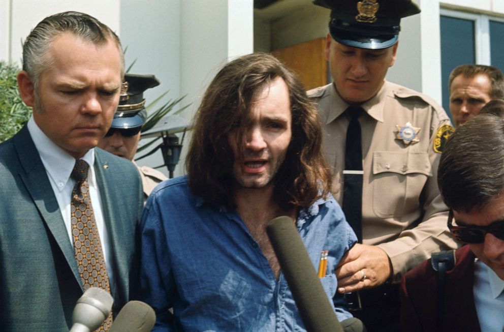 PHOTO: Charles Manson speaks with reporters as he is escorted by a deputy sheriff and his lawyer, Irving Kanarek, from a Santa Monica courthouse following a hearing in the Gary Hinman murder case.