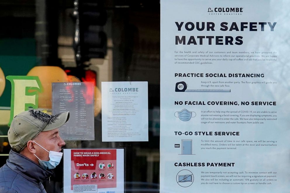 PHOTO: A man walks past a coffee shop as the store displays information signs in Chicago, Nov. 12, 2020.