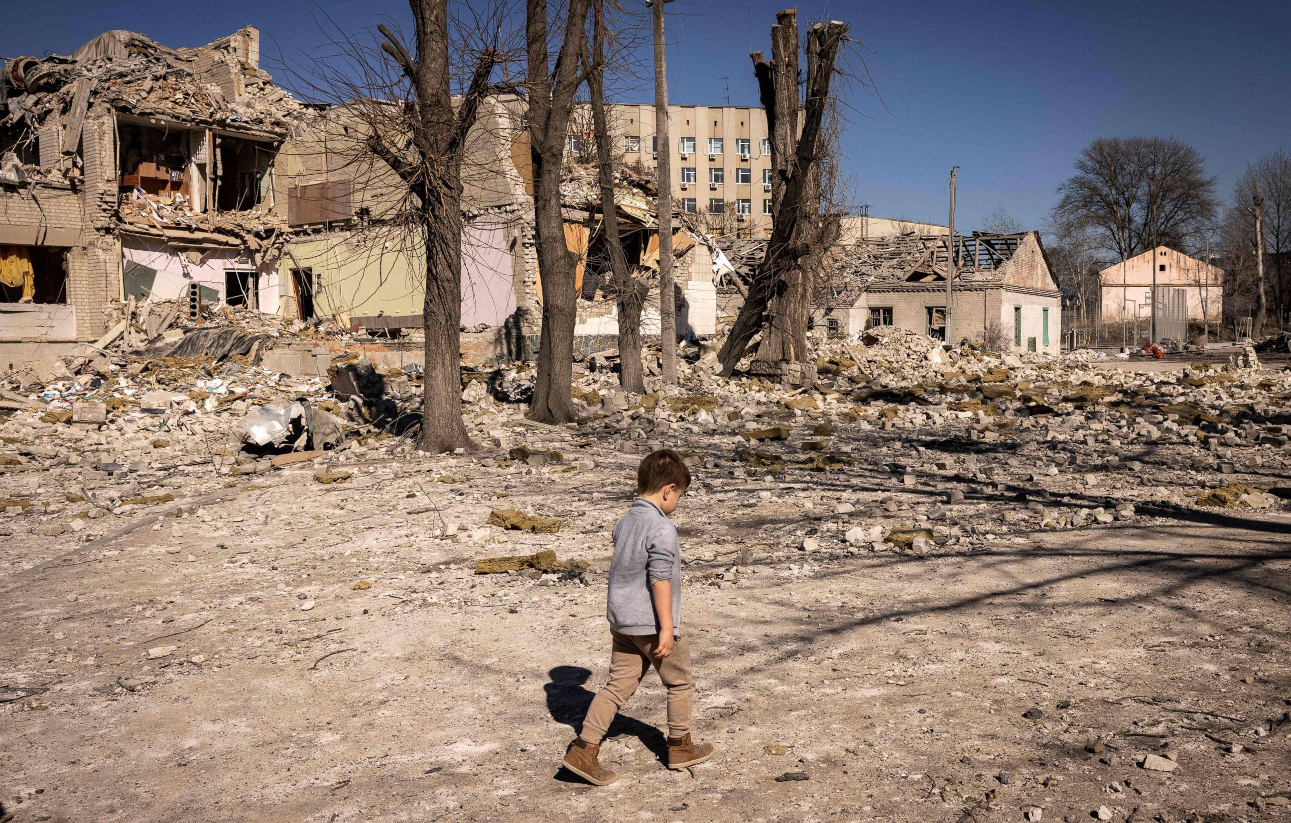 PHOTO: A child walks in front of a damaged school in Zhytomyr, northern Ukraine, on March 23, 2022, amid Russia's invasion.