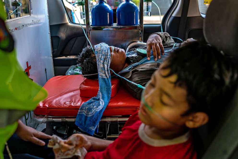 PHOTO: An anti-coup protester and a child who were exposed to tear gas receive oxygen from medics on March 1, 2021 in Yangon, Myanmar. Myanmar's military government has recently intensified a crackdown on protesters, using tear gas and live ammunition.