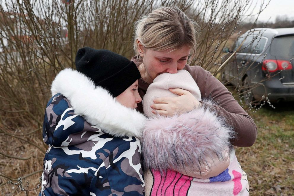 Anna Semyuk,33,hugs her children at the Beregsurany border crossing in Hungary, Feb. 26, 2022.The children were handed to Nataliya Ableyeva, 58,a stranger,with their passports on the Ukrainian side of the border by the father,who was not allowed to cross.