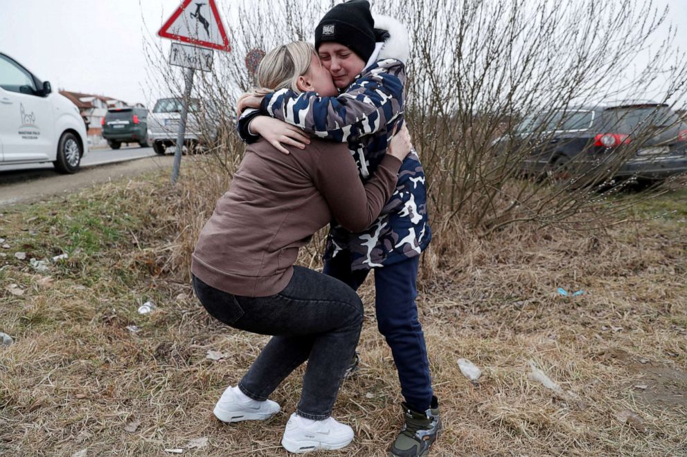 Anna Semyuk,33,hugs her children at the Beregsurany border crossing in Hungary, Feb. 26, 2022.The children were handed to Nataliya Ableyeva, 58,a stranger,with their passports on the Ukrainian side of the border by the father,who was not allowed to cross.