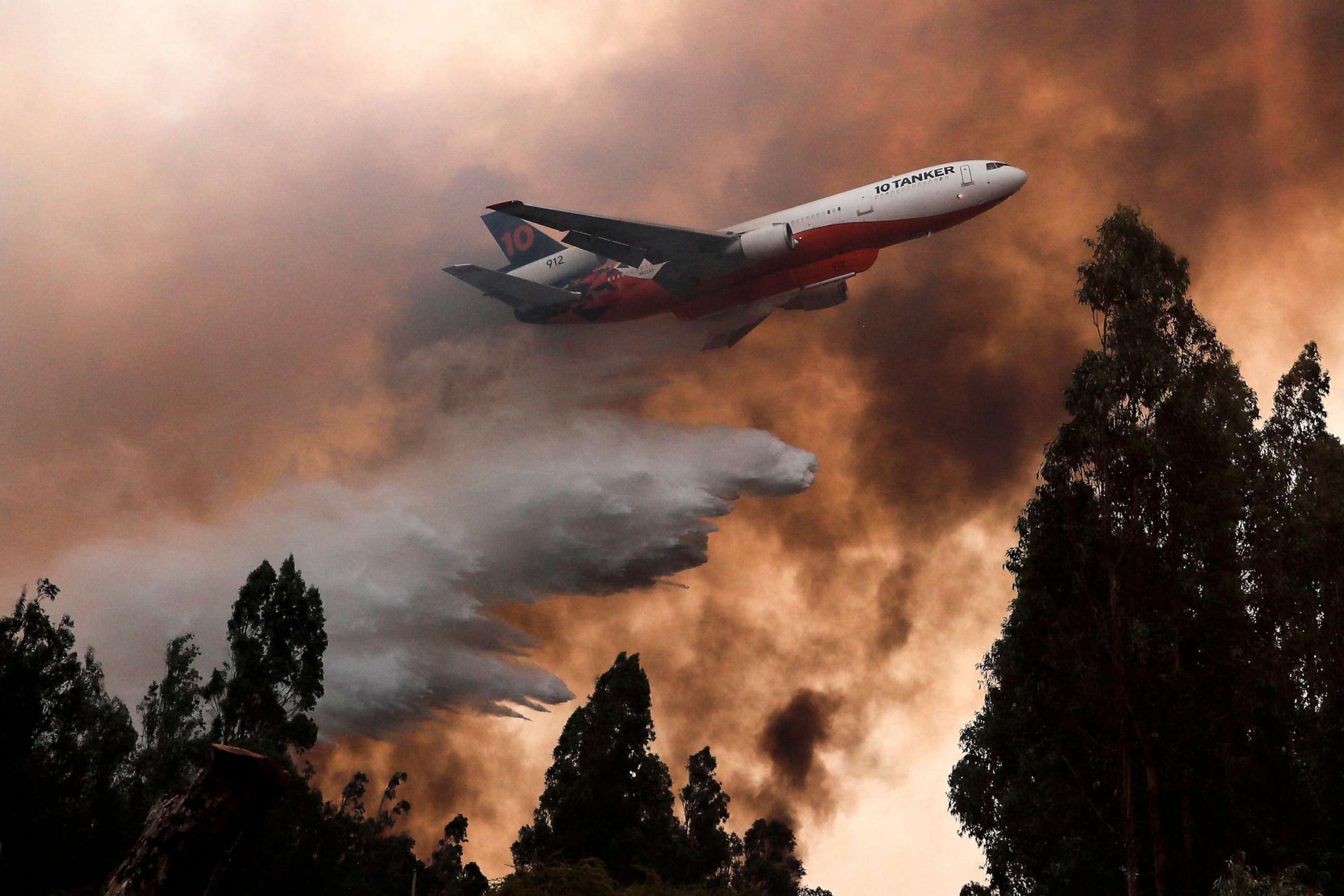 PHOTO: A 10 Tanker DC-10 fire plane throws water over a forest fire in Ninhue, Ãuble Region, in Chile, on February 10, 2023. - Forest fires have raged for more than a week in south-central Chile, leaving at least 24 people dead.