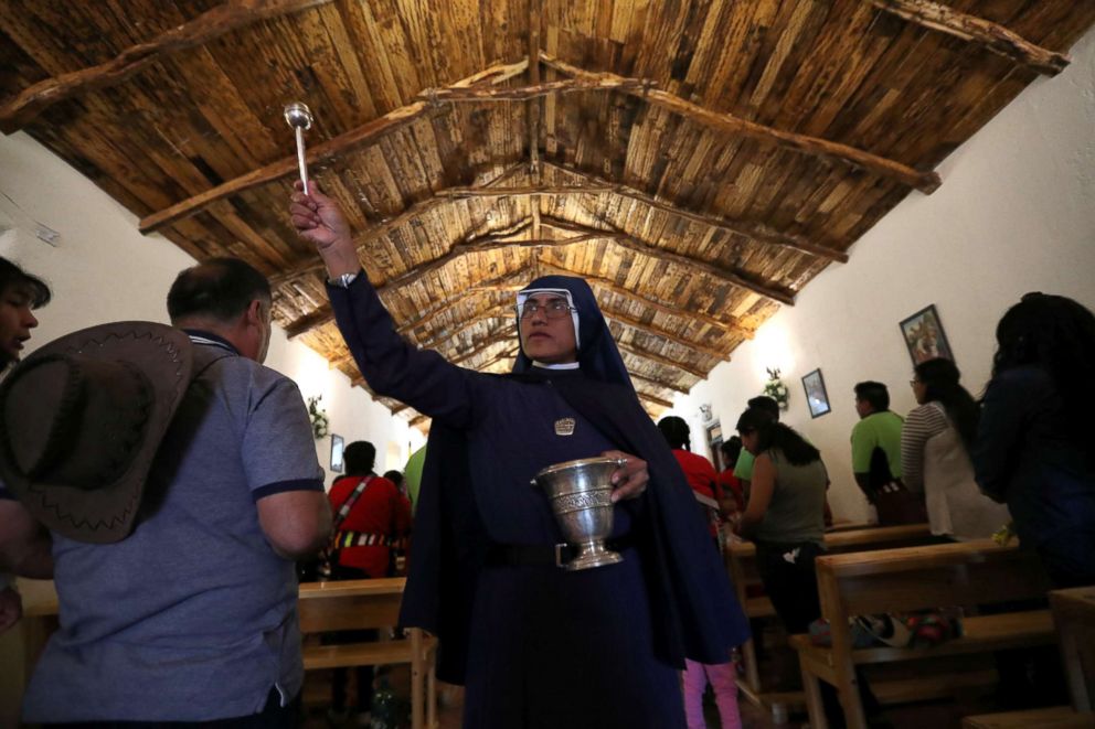 PHOTO: A nun sprinkles holy water on believers inside a church during a religious holiday in the Peine area on the Atacama salt flat in the Atacama desert, Chile, Aug. 15, 2018.