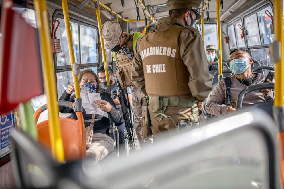 PHOTO: Authorities verify the health permits of the passengers on a public transport bus in Santiago, Chile. Sanitary checks and police controls were implemented during the first day of total lockdown in the central area of the country.  