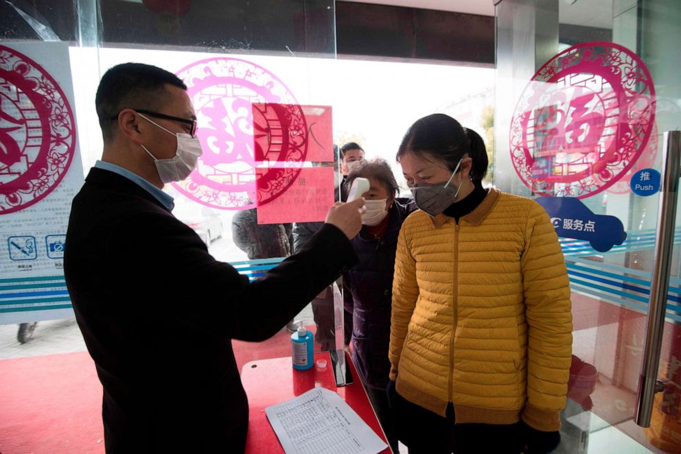 PHOTO: This photo taken on Feb. 25, 2020, shows a customer having her temperature taken at the entrance to a bank in Nantong, in China's eastern Jiangsu province, as the country is hit by an outbreak of the novel coronavirus.