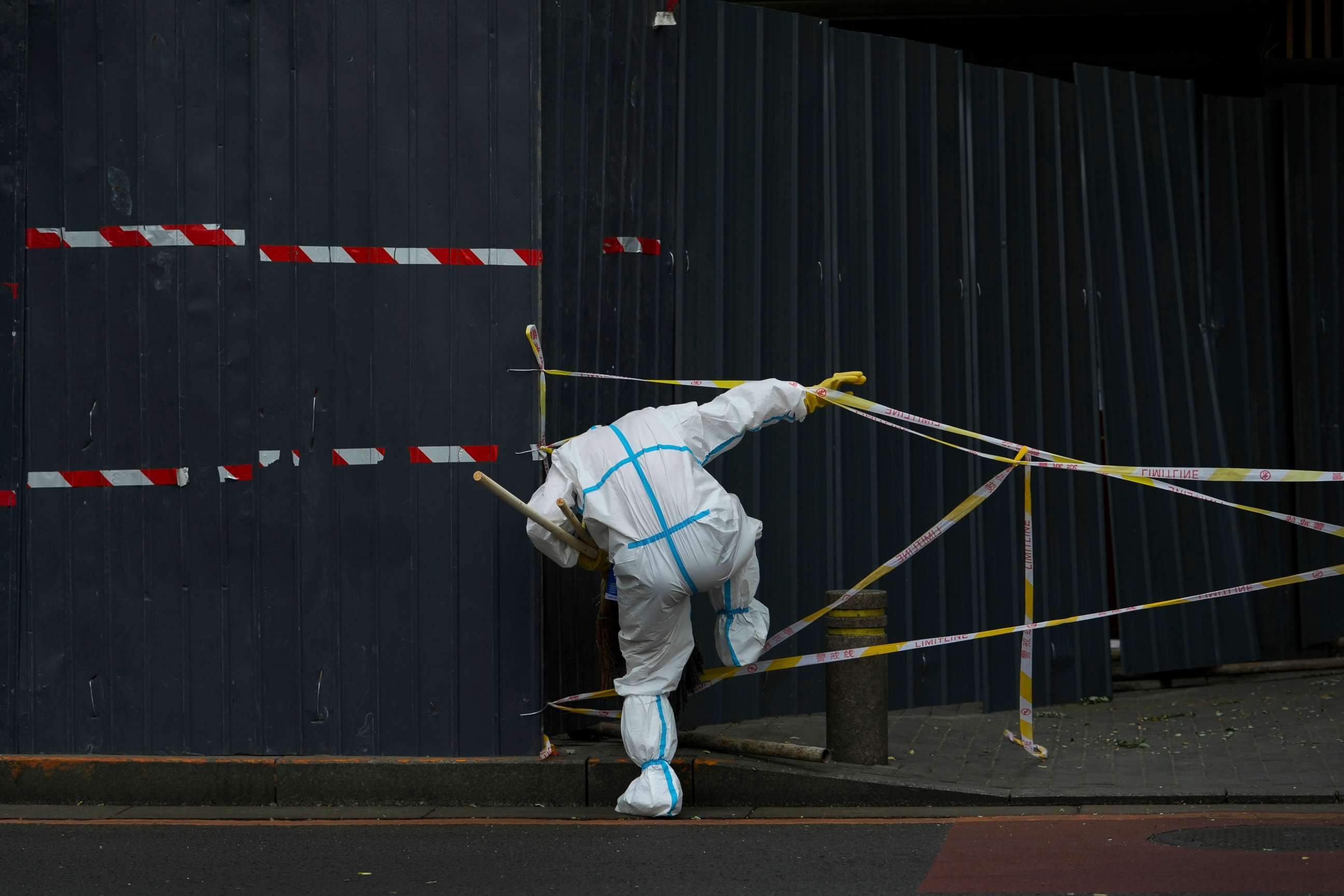 PHOTO: A worker in protective suit walks through the caution tapes along metal barricades retail shops that has been locked down as part of COVID-19 controls in Beijing, China, on June 26, 2022.