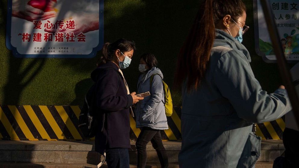 PHOTO: Commuters wearing face masks walk along a street in the central business district in Beijing, on Nov. 3, 2022. Access to an industrial zone in the central Chinese city of Zhengzhou was suspended after the city reported dozens of coronavirus cases.