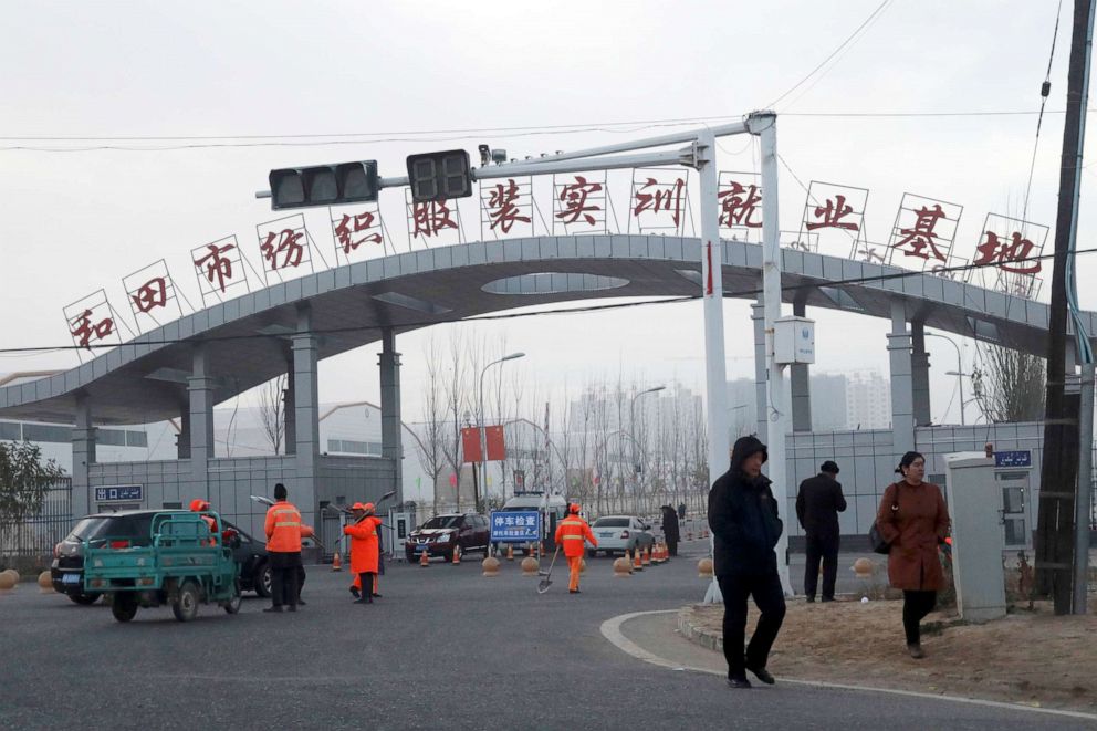 PHOTO: In this Dec. 5, 2018, file photo, residents pass by the entrance to the "Hotan City apparel employment training base" where Hetian Taida Apparel Co. has a factory in Hotan in western China's Xinjiang region.