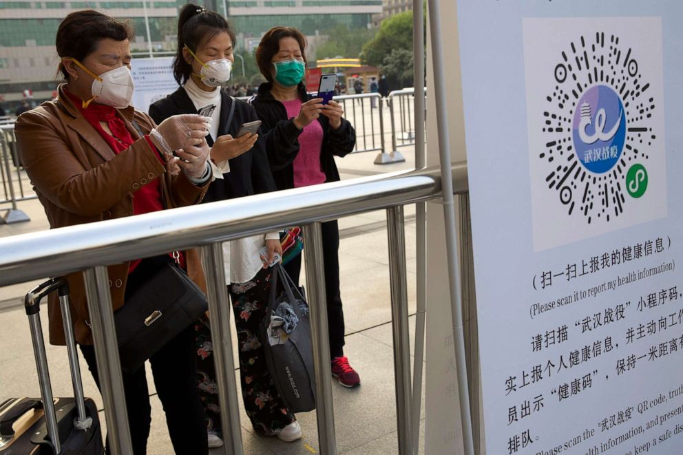 PHOTO: Passengers wearing face masks to protect against the spread of new coronavirus use their smartphones scan a QR code to generate a health report outside of Hankou train station in Wuhan in central China's Hubei Province, April 8, 2020.