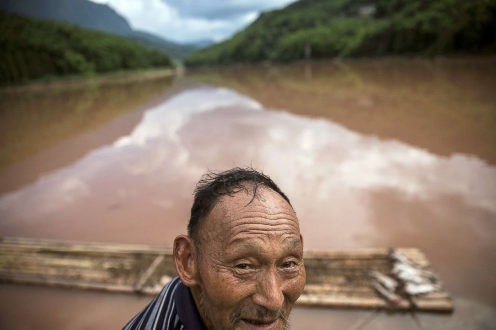 PHOTO: A 70-year old farmer surnamed Zhang stands near the fish he caught on the Zhougong River near Ya'an in Sichuan province, China, Aug. 4, 2018.