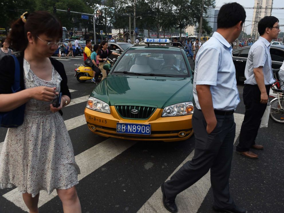 PHOTO: A taxi driver squeezes past people on a pedestrian crossing in Beijing on June 10, 2014.