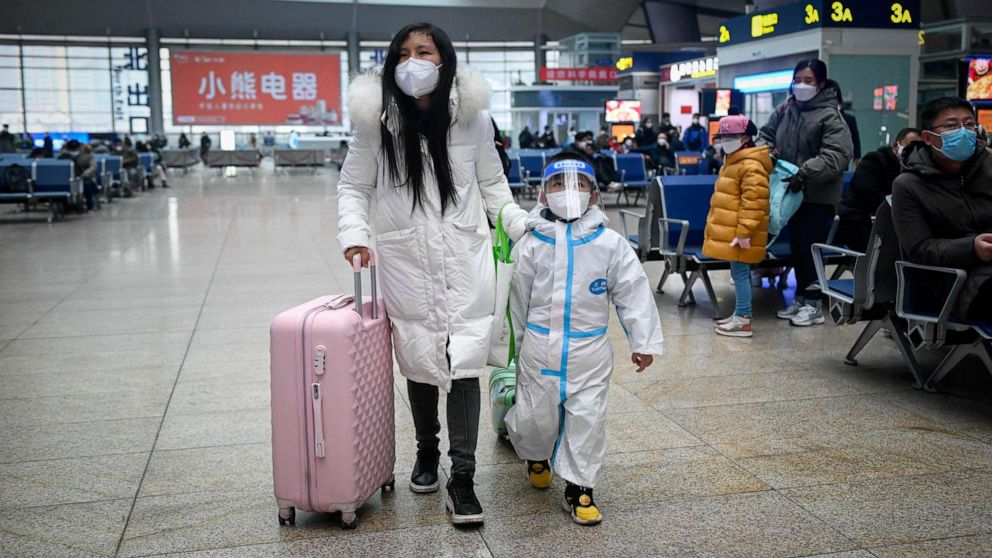 PHOTO: A woman leading child with personal protective equipment walks at a railway station in Beijing on Jan. 12, 2023, as the annual migration begins with people heading back to their hometowns for Lunar New Year celebrations.