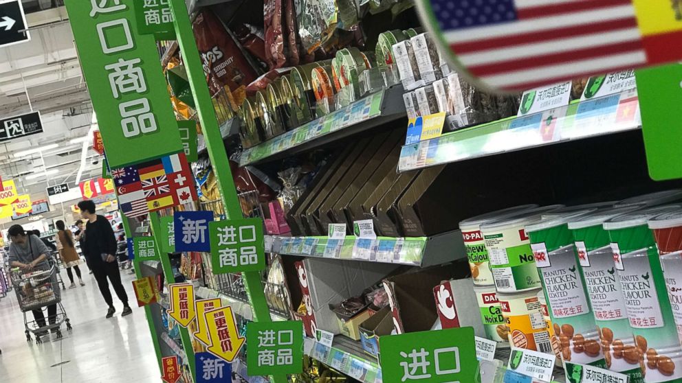 In this Monday, April 2, 2018, file photo, women push a shopping cart near nuts and sweets imported from the United States and other countries at a supermarket in Beijing.