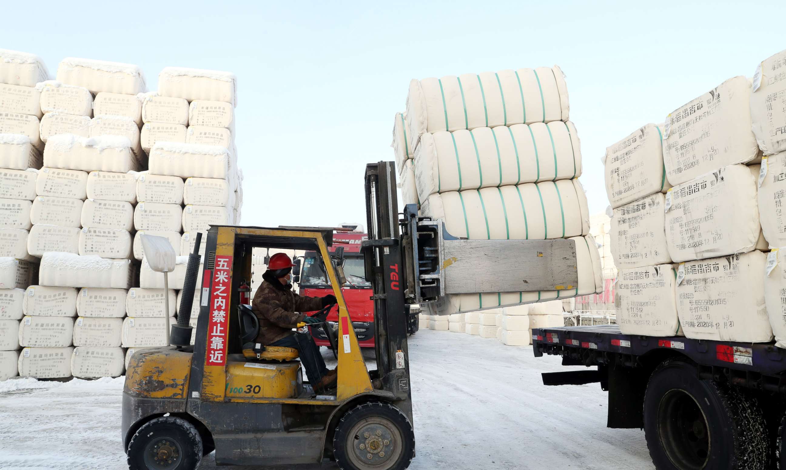 PHOTO: A worker operates a forklift truck to load bales of cotton onto a truck at a cotton warehouse on Dec. 23, 2020, in Urumqi, Xinjiang Uygur Autonomous Region of China.