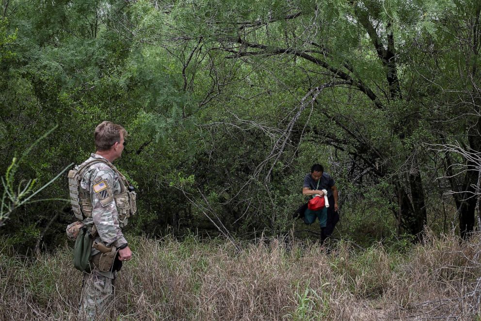 PHOTO: A member of the Texas Army National Guard asks a migrant from China to come out of his hiding place after the man and others were smuggled across the Rio Grande river into the United States from Mexico, in Fronton, Texas, on April 5, 2023.