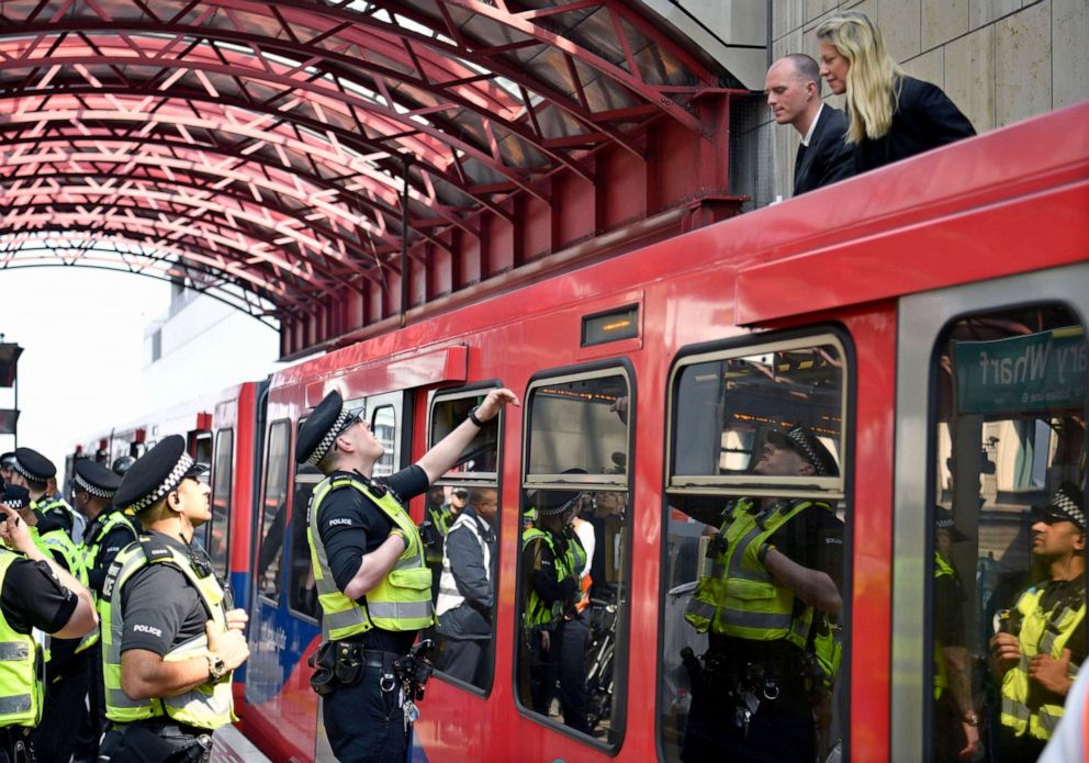 PHOTO: Police speak with protesters from the Extinction Rebellion campaign group who glued themselves to the top of a train at Canary Wharf station in London, April 17, 2019.