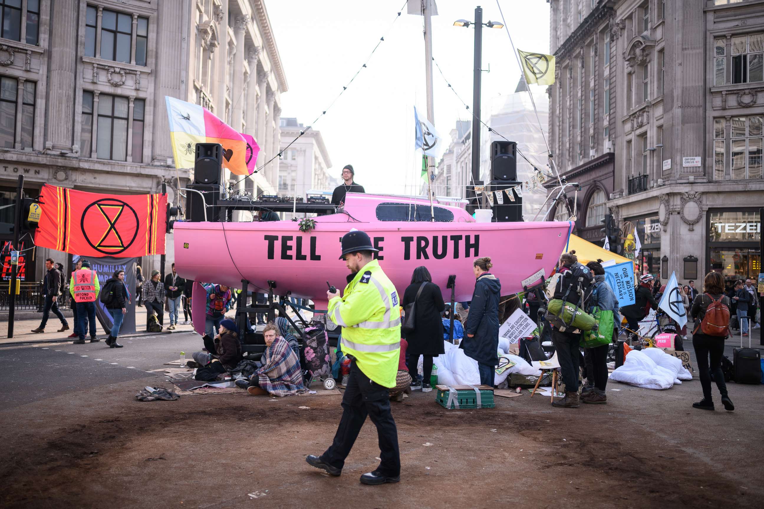 PHOTO: A police officer passes protester's tents and the Extinction Rebellion boat in the center of Oxford Circus on April 17, 2019 in London.