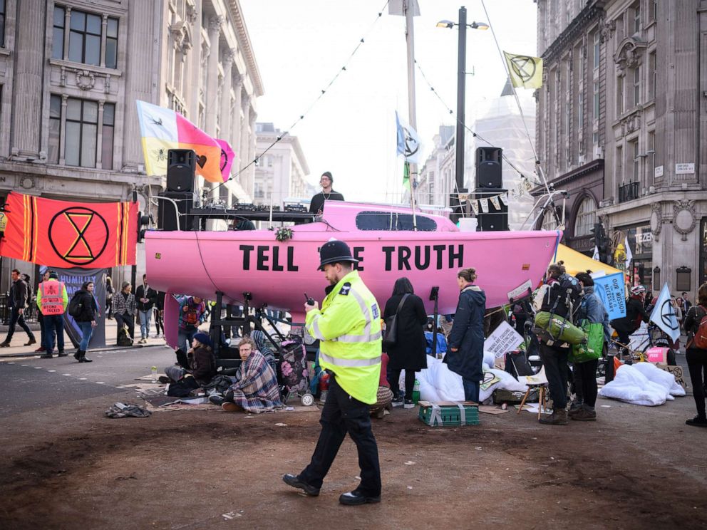 PHOTO: A police officer passes protesters tents and the Extinction Rebellion boat in the center of Oxford Circus on April 17, 2019 in London.