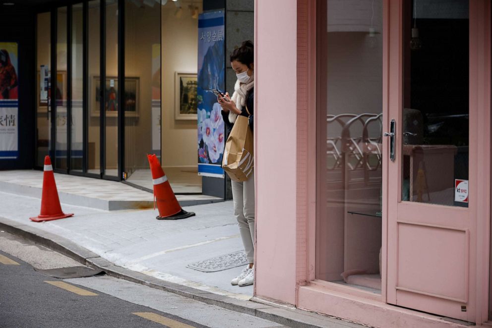 PHOTO: A woman wearing a face mask stands next to a closed cosmetic shop in a shopping district of Seoul, South Korea, on Jan. 4, 2021.