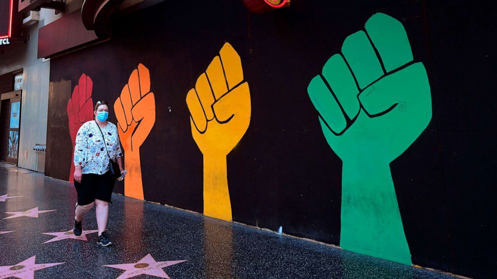 PHOTO: A pedestrian wearing a face mask to protect against the novel coronavirus walks past a boarded up and temporarily closed Hard Rock Cafe on Hollywood Boulevard in Hollywood, California, on Oct. 15.