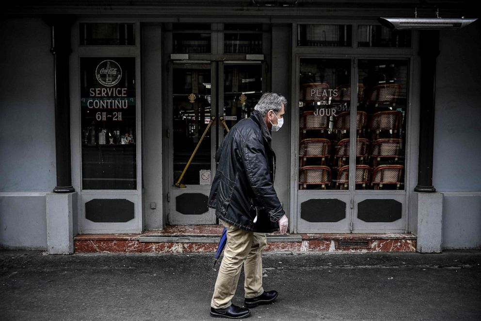PHOTO: A man wearing a protective face mask walks past a closed restaurant in Paris on May 4, 2020, on the 49th day of France's nationwide lockdown aimed at curbing the spread of the novel coronavirus.