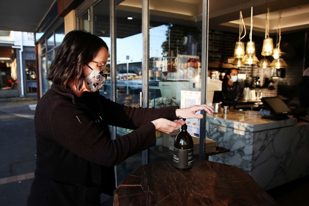 PHOTO: Jo Fahey uses hand sanitizer before getting her morning coffee at The Store in Kohimarama, a suburb of Auckland, New Zealand, as the city wakes to a return to level three lockdown on Aug. 13, 2020.