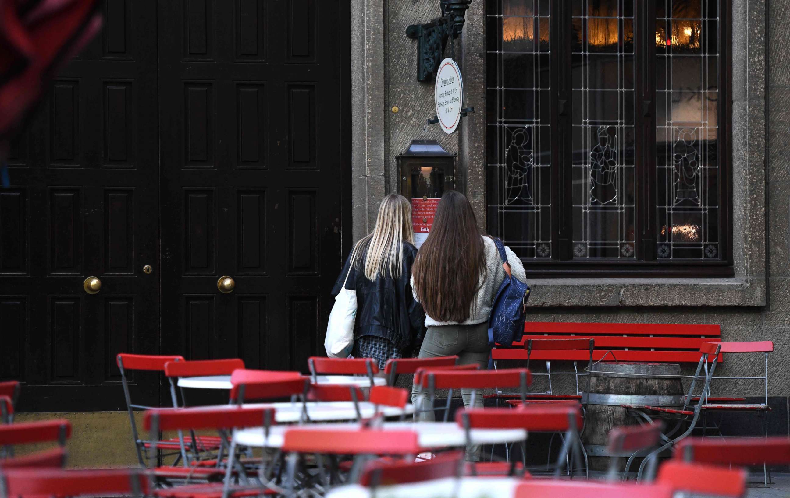 PHOTO: Two girls stand at the closed 'Frueh' beer restaurant, March 17, 2020 in Cologne, western Germany, where restaurants closed, as well as many activities slowed down or came to a halt due to the spread of the novel coronavirus COVID-19. 