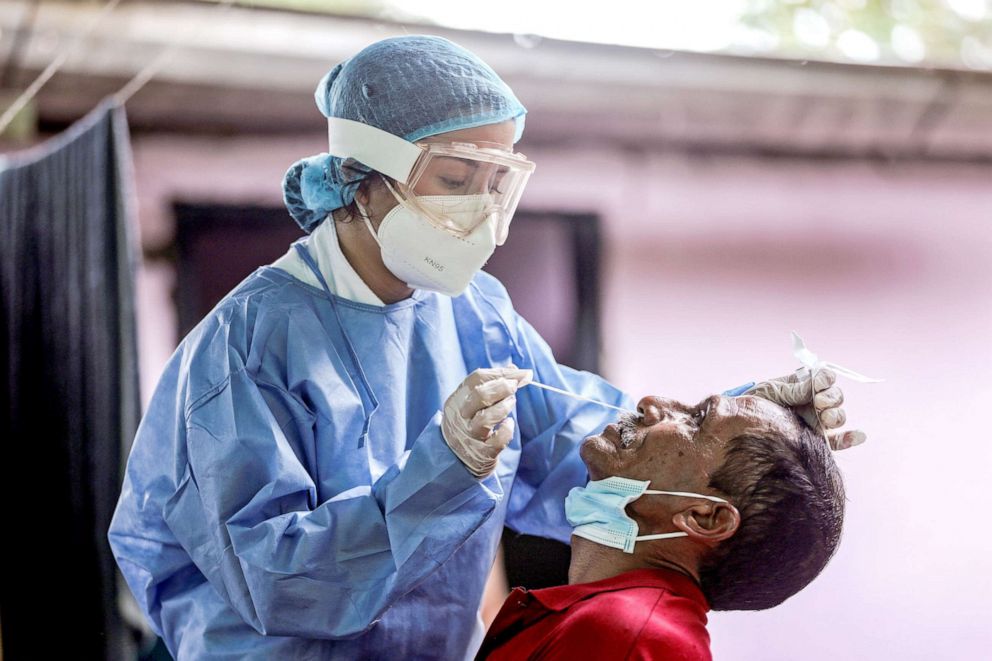 PHOTO: A member of the Colombian Red Cross medical team takes a swab sample to be tested for the coronavirus disease from a Venezuelan refugee who fled his country due to military operations, in Arauquita, Colombia, March 28, 2021.