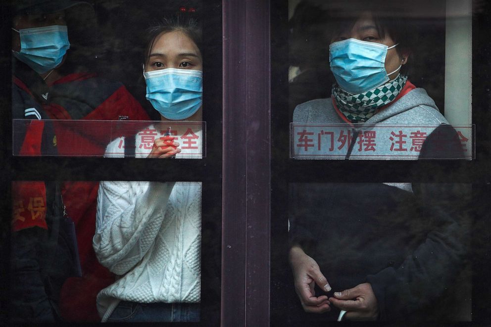 PHOTO: Commuters wearing face masks to help protect against the novel coronavirus look out from a traveling bus during the morning rush hour in Beijing, China, on Oct. 26, 2020.