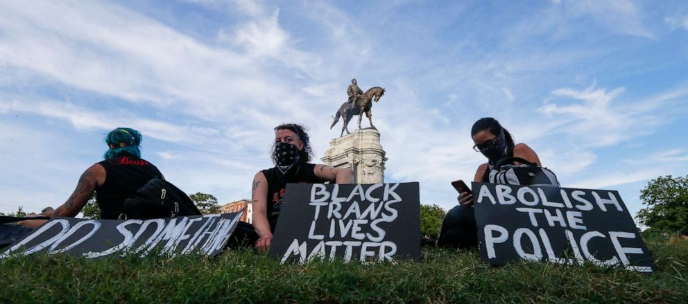 PHOTO: Protesters hold signs around the statue of Confederate Gen. Robert E. Lee on Monument Avenue, June 2, 2020, in Richmond, Va. The crowd protesting police brutality chanted "Tear it down."