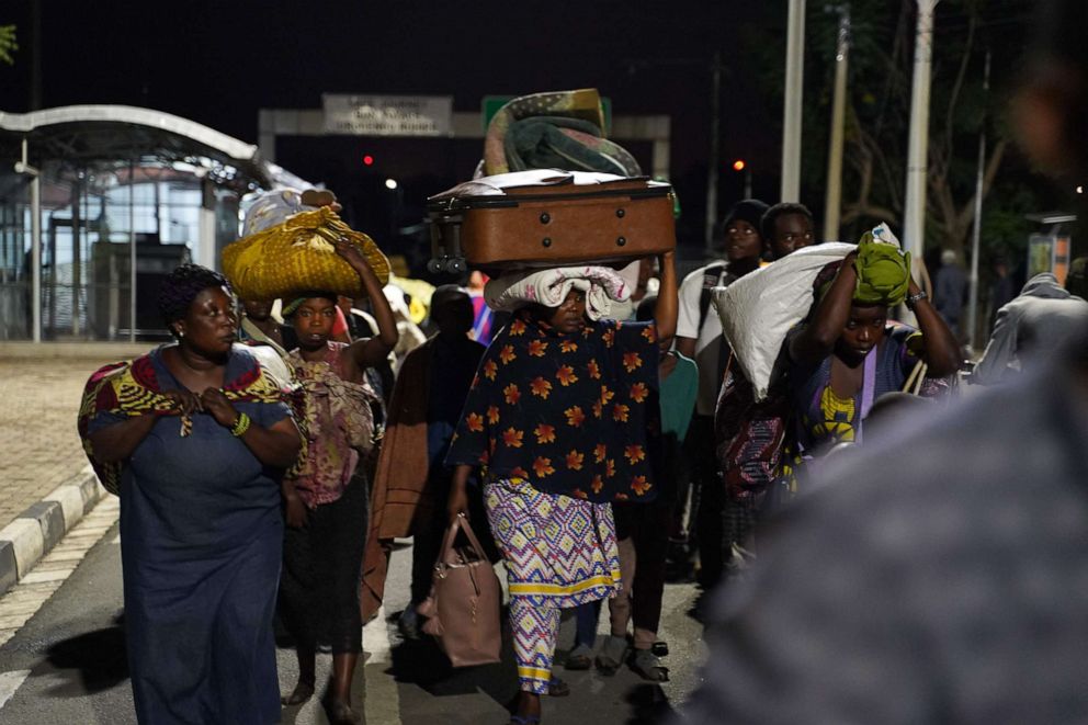PHOTO: People carry their belongings as they cross into Rwanda from the Democratic Republic of Congo on May 23, 2021, after fleeing from the Mount Nyiragongo volcanic eruption.