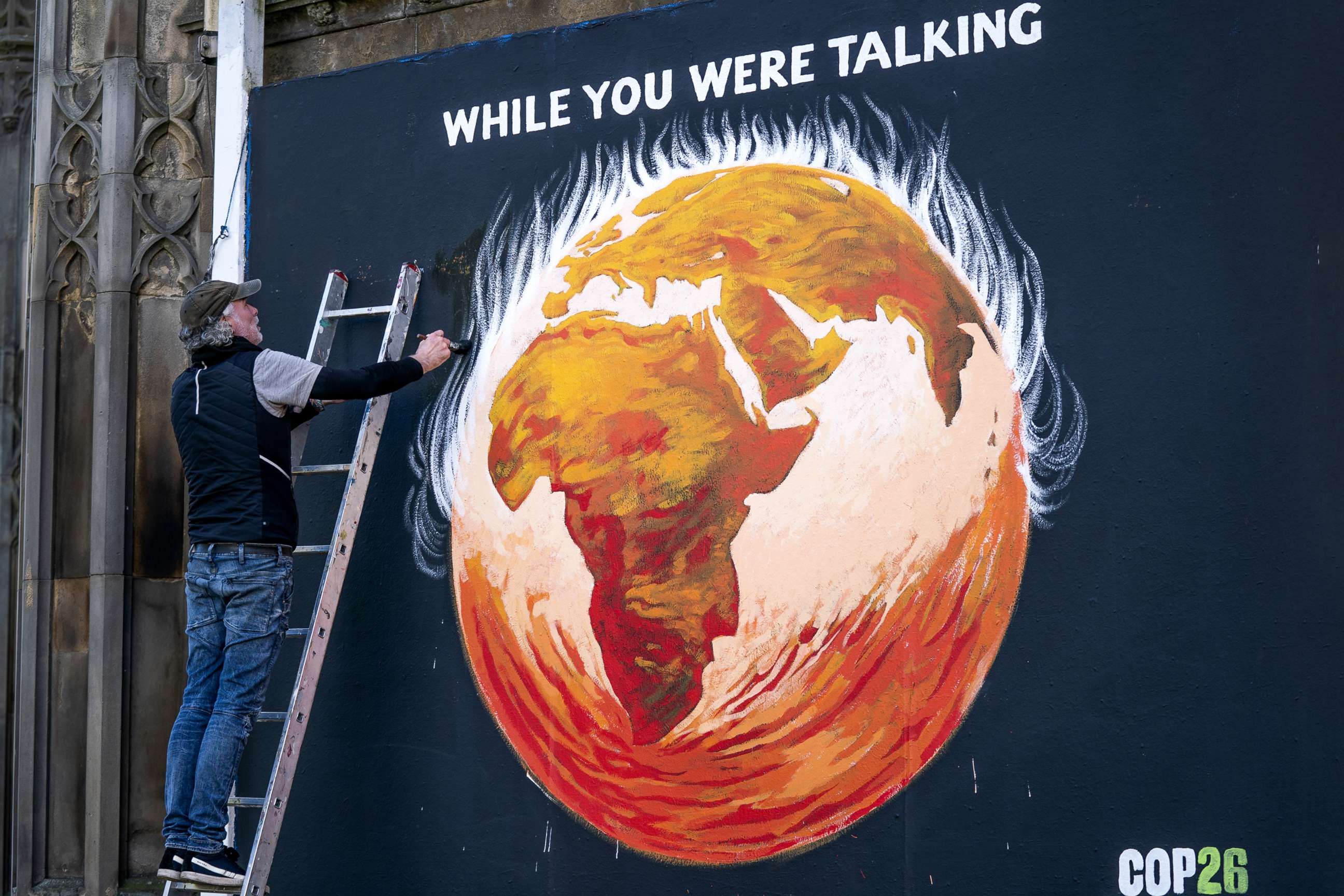 PHOTO: Artist Greg Mitchell completes his climate-crisis themed mural that depicts the Earth on fire and reads "While you were talking," on the side of St. John's Church in Edinburgh, Scotland, Oct. 25, 2021, to coincide with the Cop26 in Glasgow.