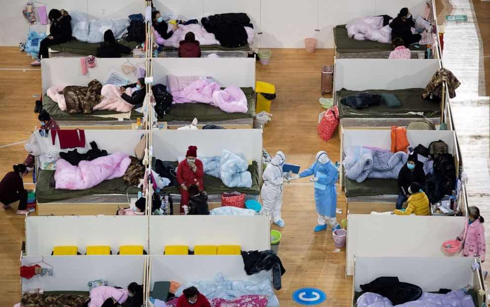 PHOTO: This photo taken on February 18, 2020 shows Medical personnel walk among patients with mild symptoms of the COVID-19 coronavirus at night in the temporary Fangcai Hospital set up in a sports stadium in Wuhan, China. 