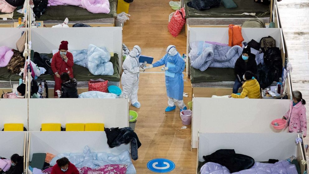 PHOTO: This photo taken on Feb. 18, 2020, shows Medical personnel walk among patients with mild symptoms of the COVID-19 coronavirus at night in the temporary Fangcai Hospital set up in a sports stadium in Wuhan, China. 