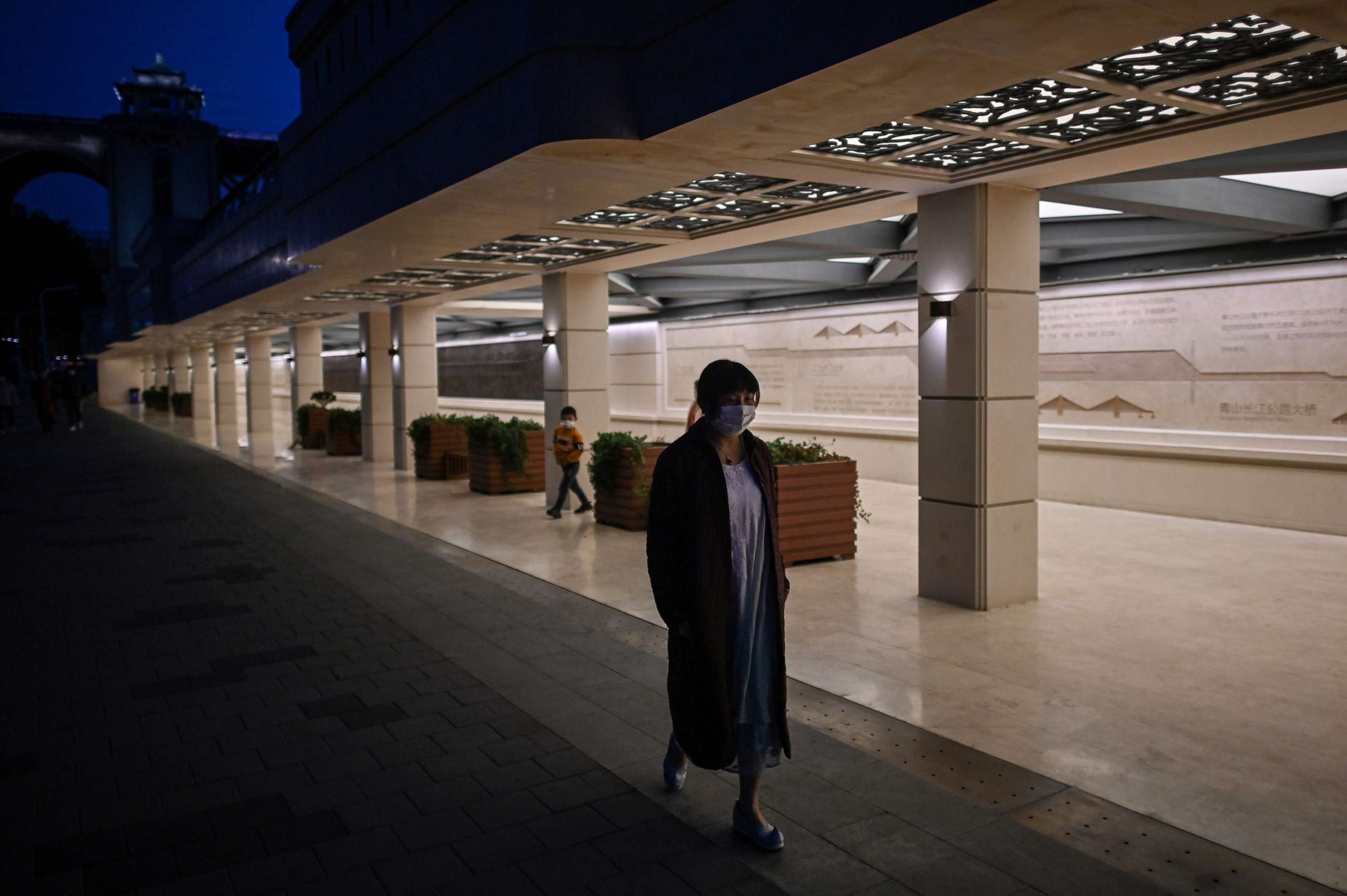 PHOTO: A woman wearing a face mask walks along a street near to Wuhan Bridge in Wuhan, in China's central Hubei province, April 13, 2020. 