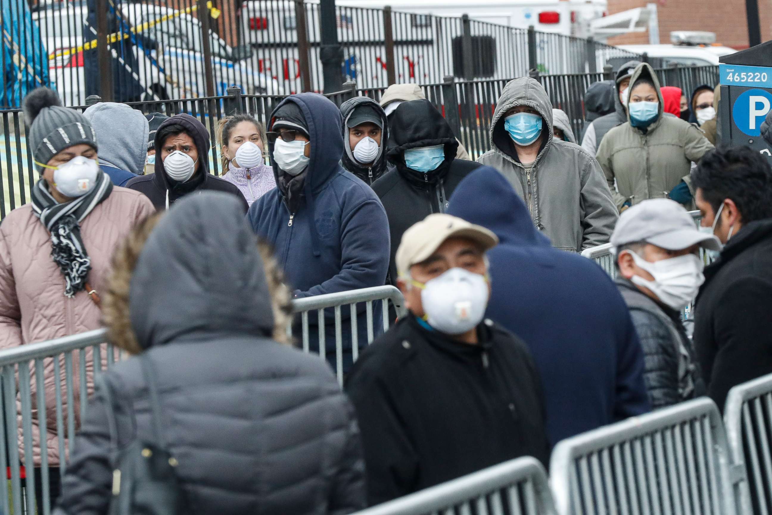 PHOTO: Patients wear personal protective equipment while maintaining social distancing as they wait in line for a COVID-19 test at Elmhurst Hospital Center, March 25, 2020, in New York.