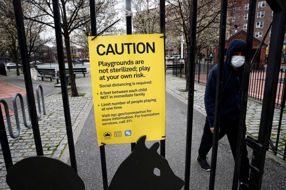 PHOTO: A pedestrian wears personal protective equipment while exercising alone to maintain social distancing at a playground, Wednesday, March 25, 2020, in New York.