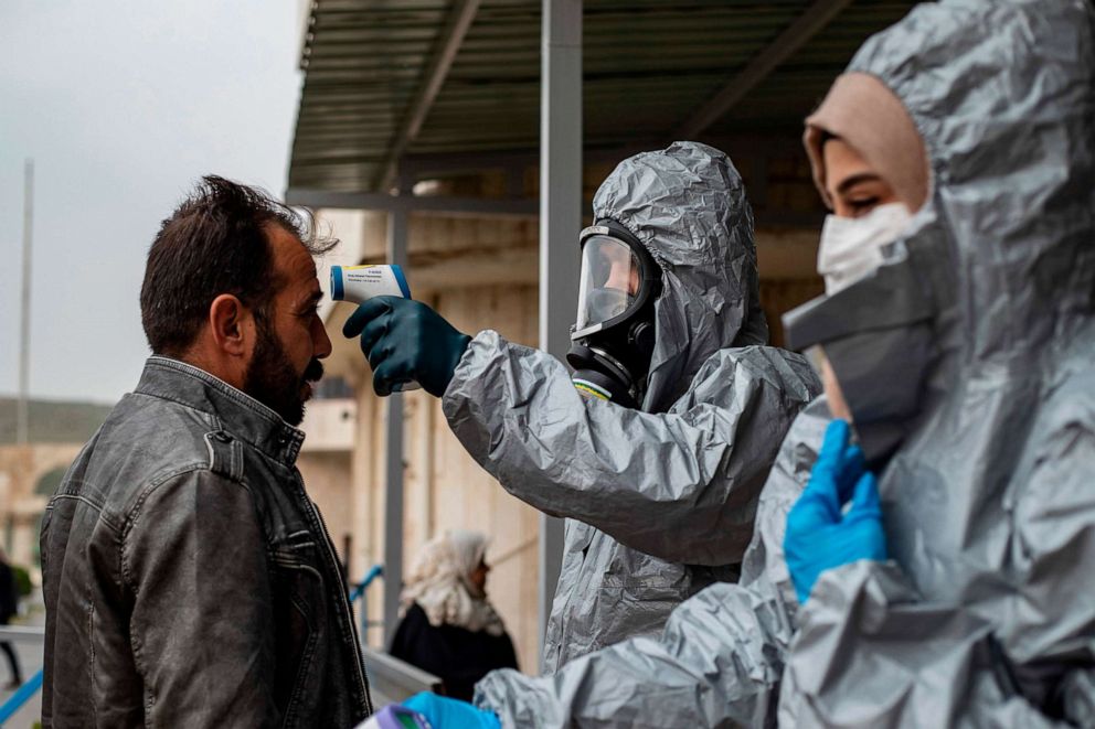 PHOTO: Medics check the body temperature of passengers, as a preventive measure against the coronavirus, upon their arrival by bus in Syria's Kurdish area from Iraqi Kurdistan via the Semalka border crossing in Syria, March 1, 2020. 