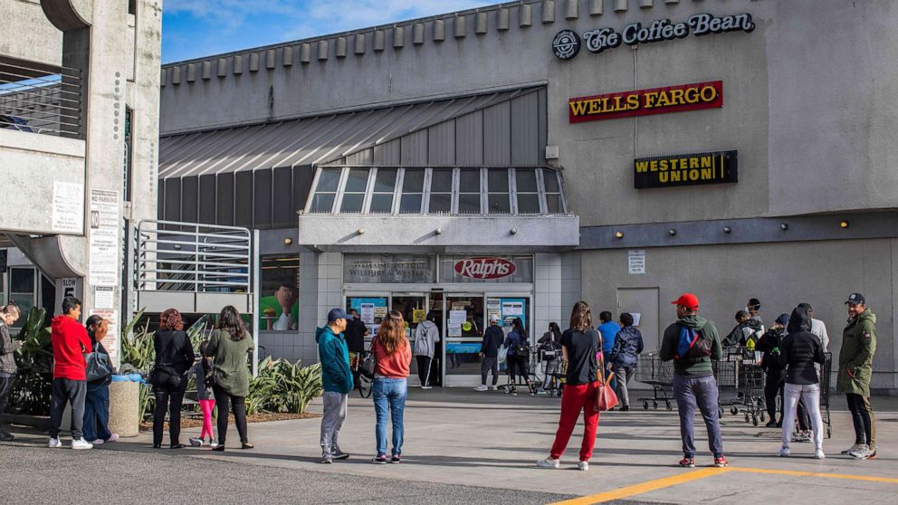 PHOTO: People wait in line to buy food at a grocery store in Los Angeles, March 21, 2020.