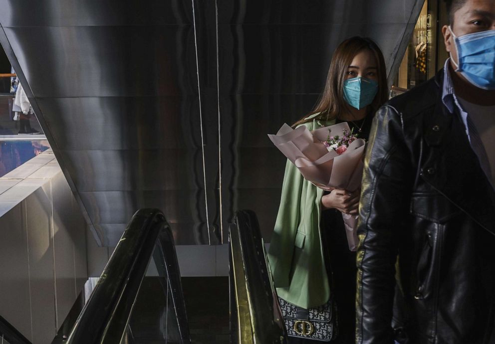 PHOTO: A woman wears a protective mask as she carries flowers at a shopping mall, March 7, 2020, in Beijing, China.