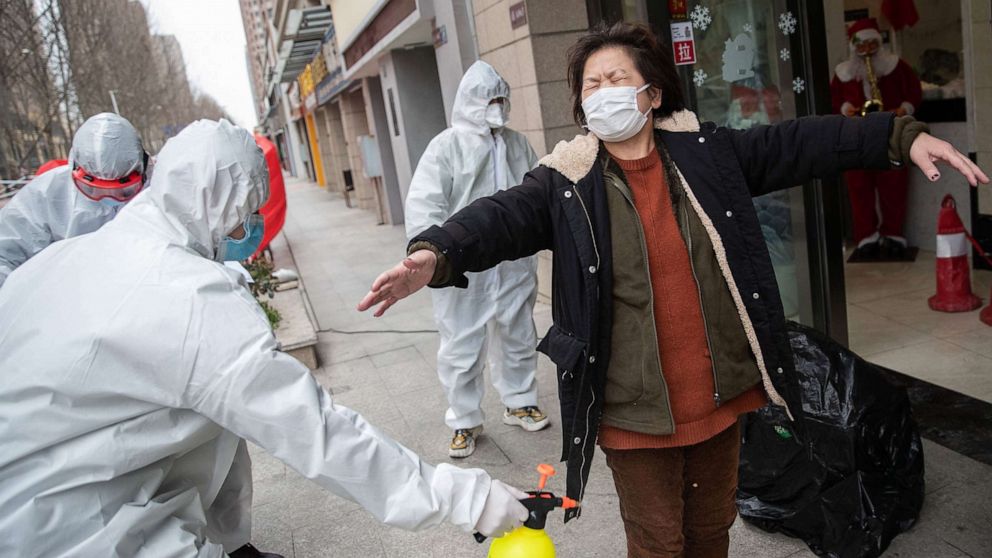PHOTO: A woman who has recovered from the coronavirus is disinfected by volunteers as she arrives at a hotel for a 14-day quarantine after being discharged from a hospital in Wuhan, in China, March 1, 2020.