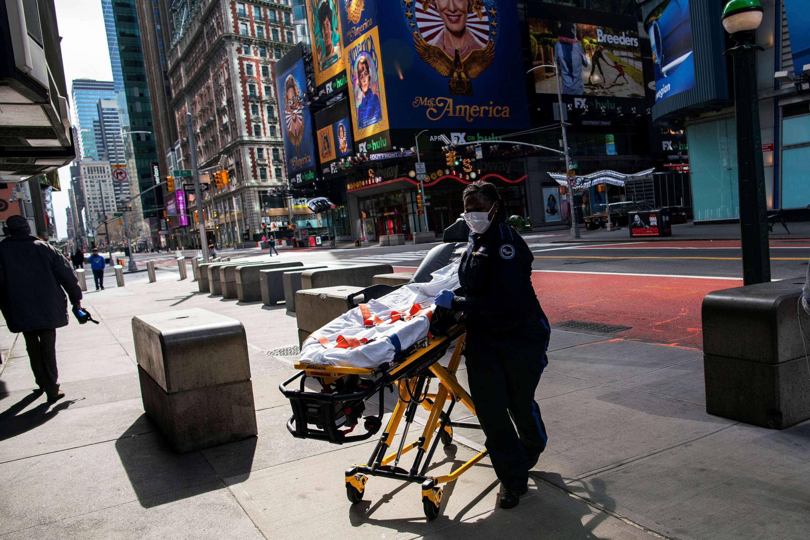 PHOTO: A health worker arrives to the subway station wearing a face mask as people walk around Times Square as the coronavirus outbreak continues in New York, March 21, 2020.  