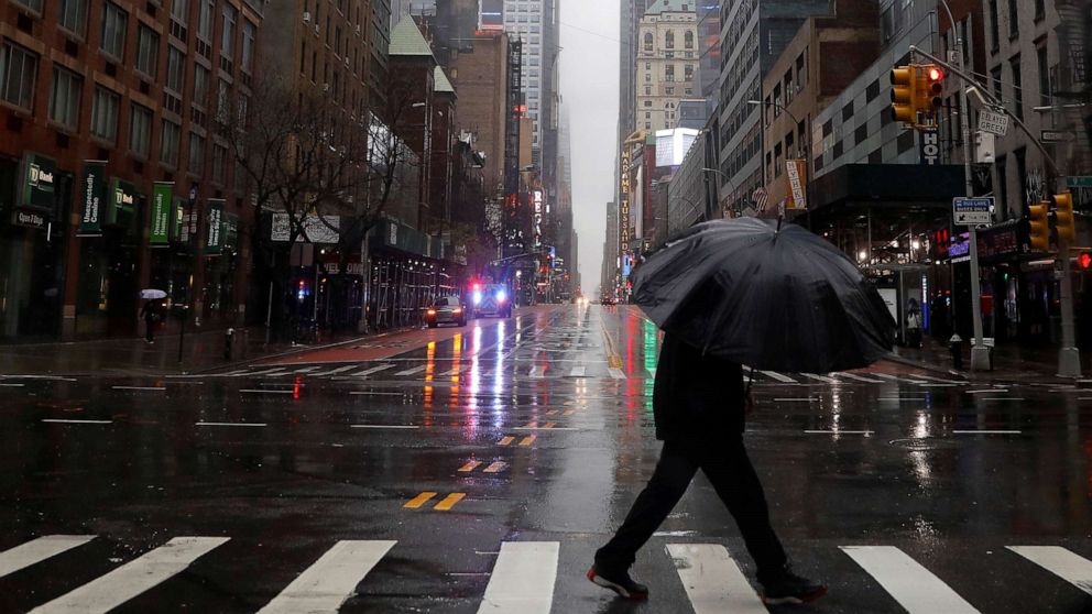 PHOTO: A man walks in heavy rain and high winds across a nearly empty West 42nd street in Manhattan during the outbreak of the coronavirus disease (COVID-19) in New York, April 13, 2020. 