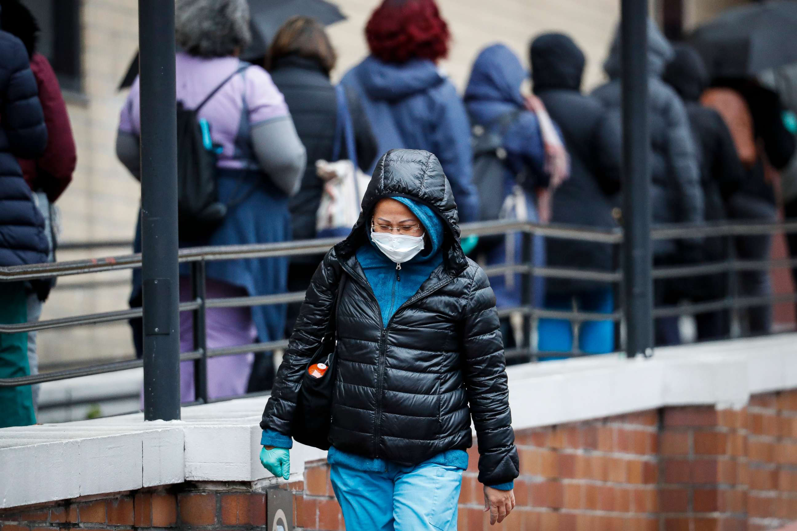 PHOTO: A medical worker walks past a line of workers and visitors waiting to be tested for coronavirus, at the main entrance to the Department of Veterans Affairs Medical Center, March 23, 2020, in New York.  