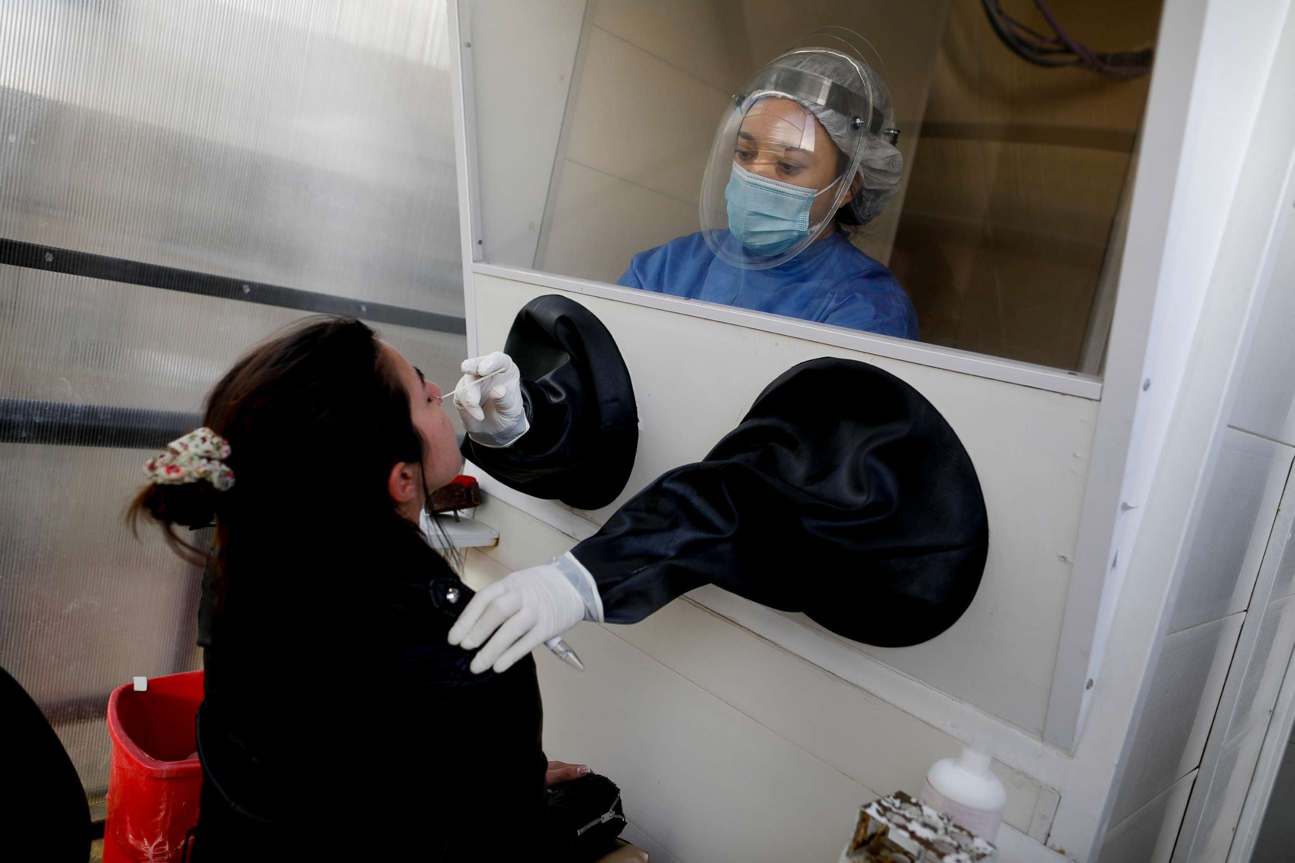 PHOTO: Healthcare worker Mariela Jacobo conducts a nasal swab test for COVID-19 from inside a freestanding coronavirus testing isolation booth, at the Posadas hospital, in Buenos Aires, Argentina, Sept. 17, 2020. 