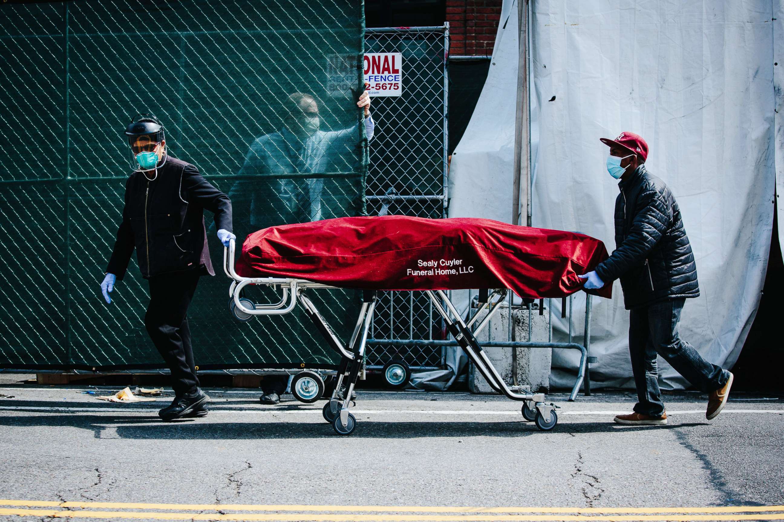 PHOTO: Hospital employees and funeral service employees transfer a body from a temporary mobile morgue into a funeral home vehicle outside of the Brooklyn Hospital Center, in Brooklyn, New York, April 8, 2020.